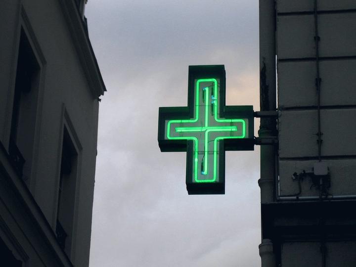 Croix de pharmacie à contour lumineux fin sur une façade ancienne